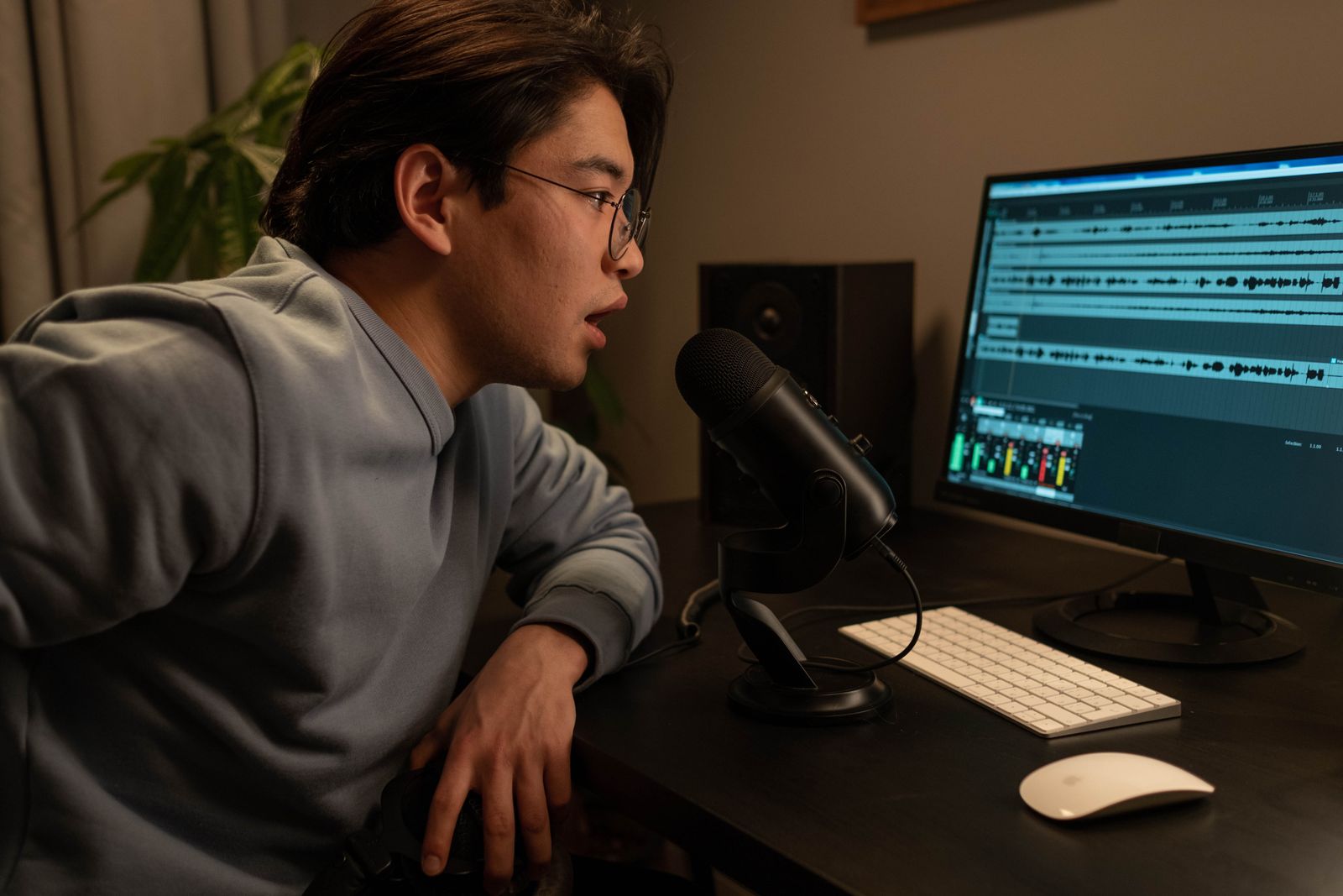 A producer adjusting dials on a mixing board beside a podcast microphone